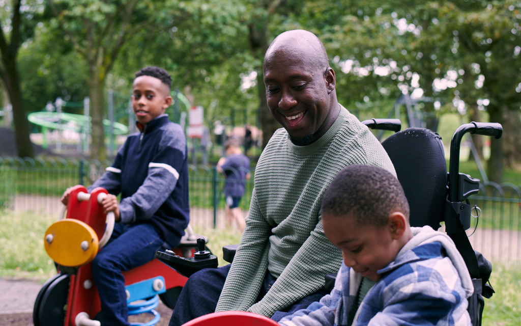 A man and his two sons play on equipment in a park