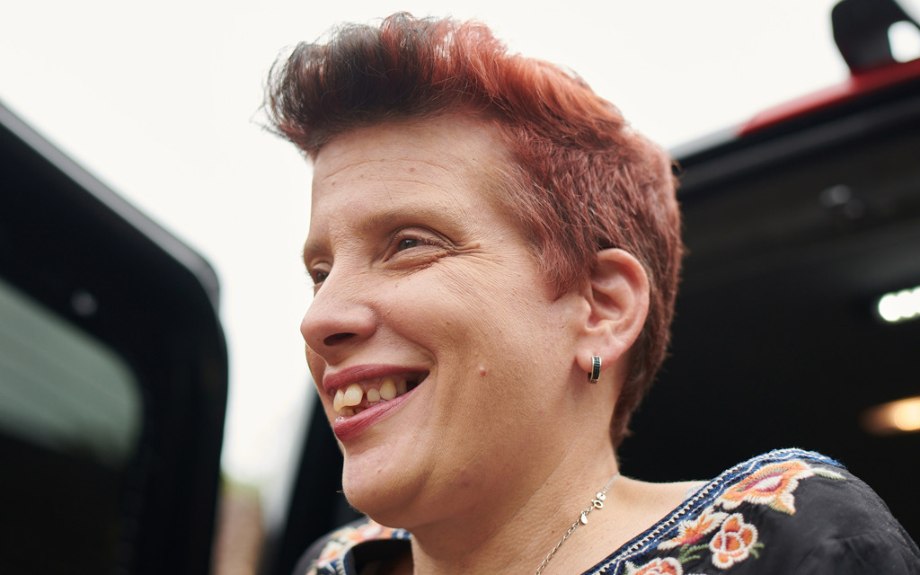 A close up of a woman's face. She is smiling and looking into the distance.