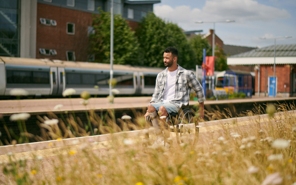 A man in a wheelchair is on a train station platform on a sunny day