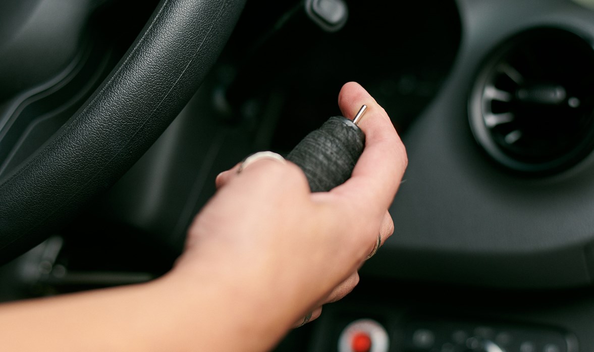 A woman's hand sits on a hand control for a car