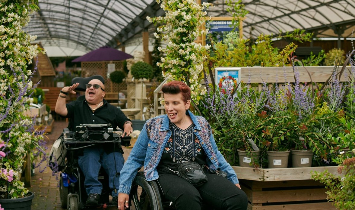 Angela and Pete are wheeling through their local garden centre looking at all the plants and chatting.