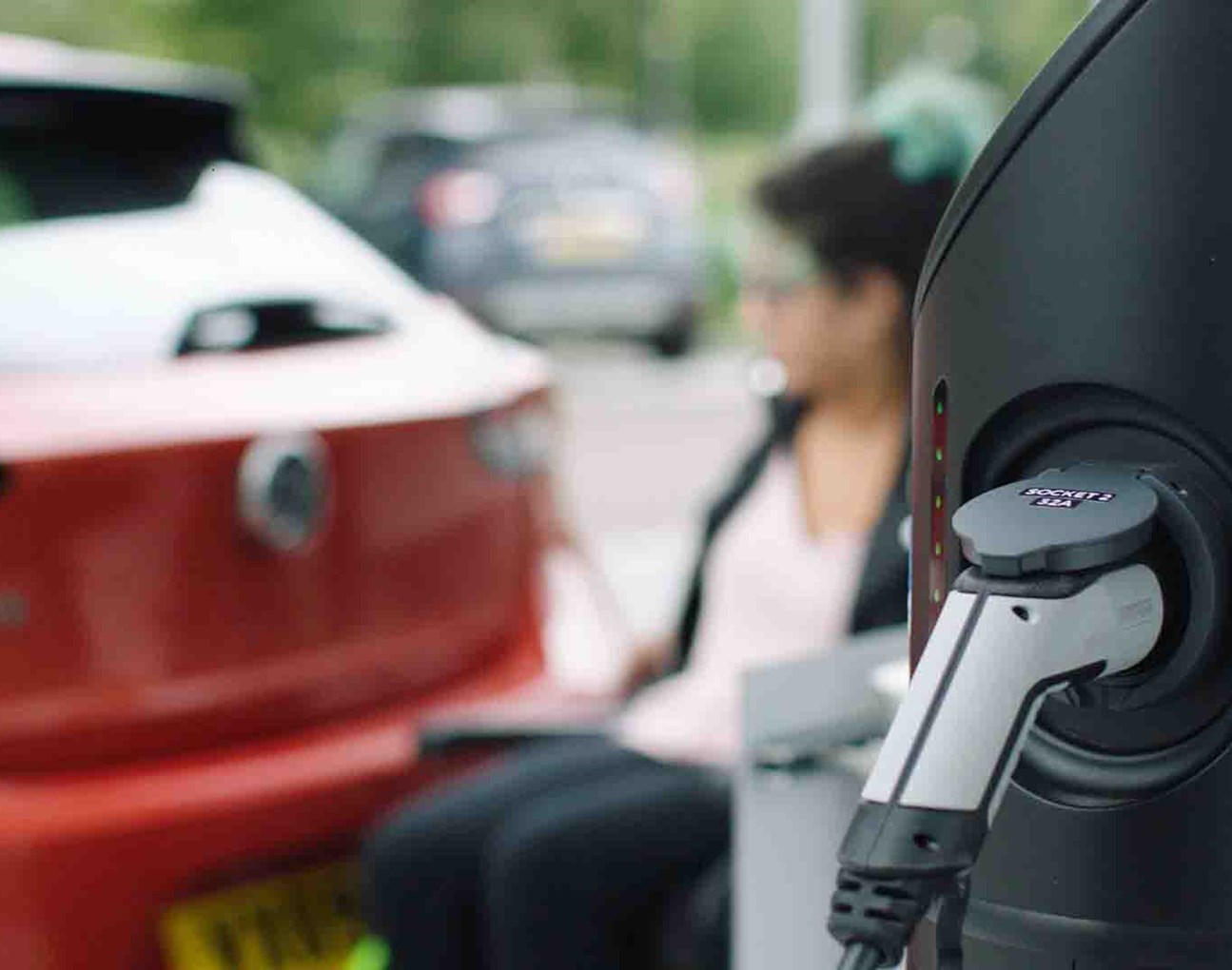 Electric vehicle charging-point and a lady next to a car