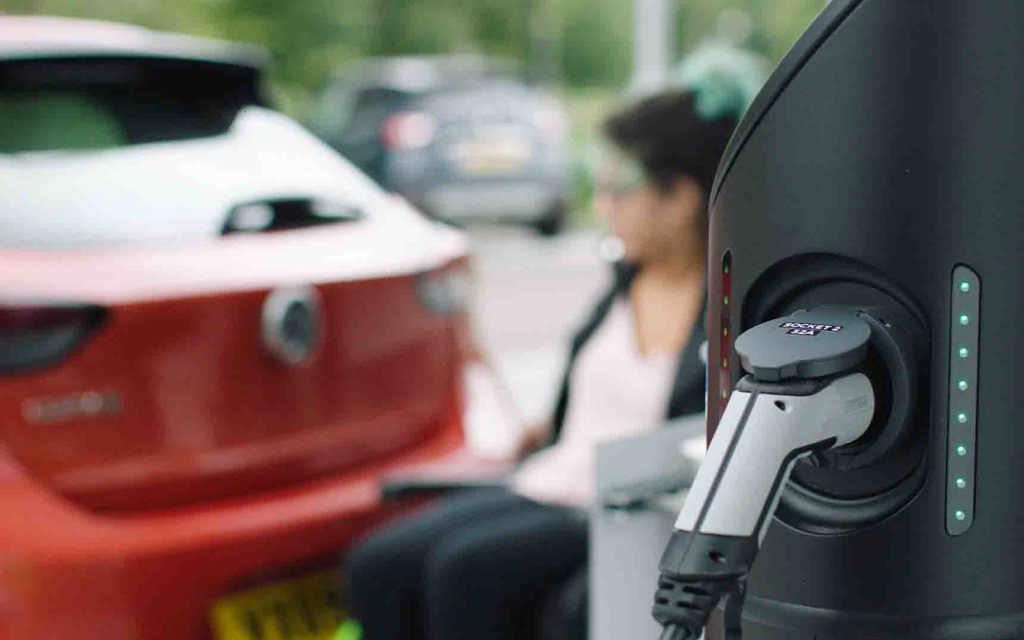 Electric vehicle charging-point and a lady next to a car