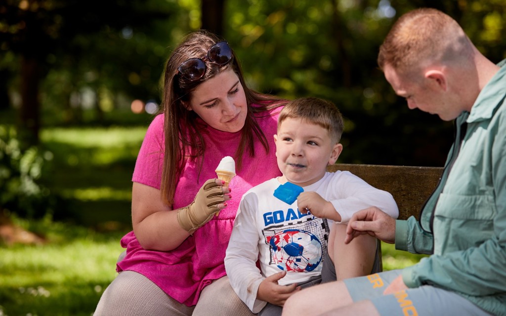 Jess is sitting with her partner and son, they are all eating an ice cream and enjoying the weather.