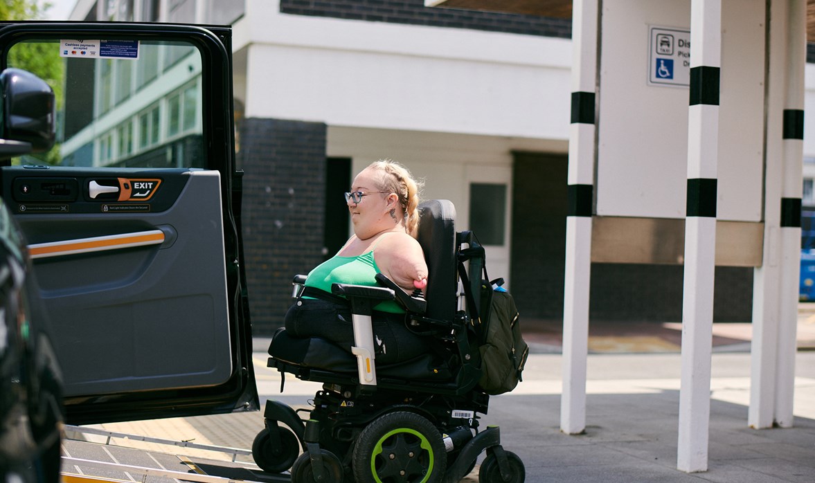 A woman in a wheelchair entering a taxi